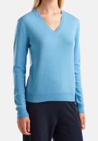 Vaaleansininen v-kaula-aukkoinen neulepaita, valmistettu pehmeästä kankaasta. Siinä on pitkät hihat sekä resorit hihansuissa ja helmassa. Erityinen tekstuuri lisää syvyyttä.