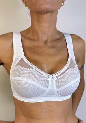 Sostenedor blanco con tirantes anchos, detalles de encaje en el busto y un pequeño lazo en el centro. Tejido texturizado con inserción de malla.