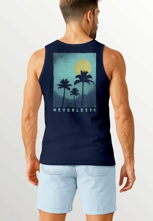 A man viewed from the back wears a navy tank top featuring a graphic of palm trees and a sun, paired with light blue shorts.