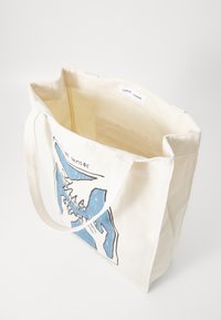 Canvas tote bag in cream with blue graphic design. Features two sturdy handles and a spacious interior with a plain lining.