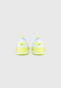 Ζεύγος αθλητικών παπουτσιών σε λευκό και νέον κίτρινο, ορατών από πίσω, με το λογότυπο της μάρκας στη φτέρνα και ετικέτες έλξης στην κορυφή.