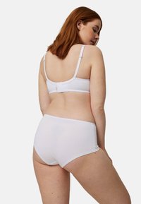Conjunto de sujetador y braguita a juego de algodón blanco. El sujetador tiene tirantes ajustables y cierre de gancho; ambas piezas tienen una textura suave.