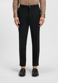 Zwarte op maat gemaakte broek met een gladde textuur, met een rechte pijp, voorkeursplooien en een knoopsluiting bij de taille.
