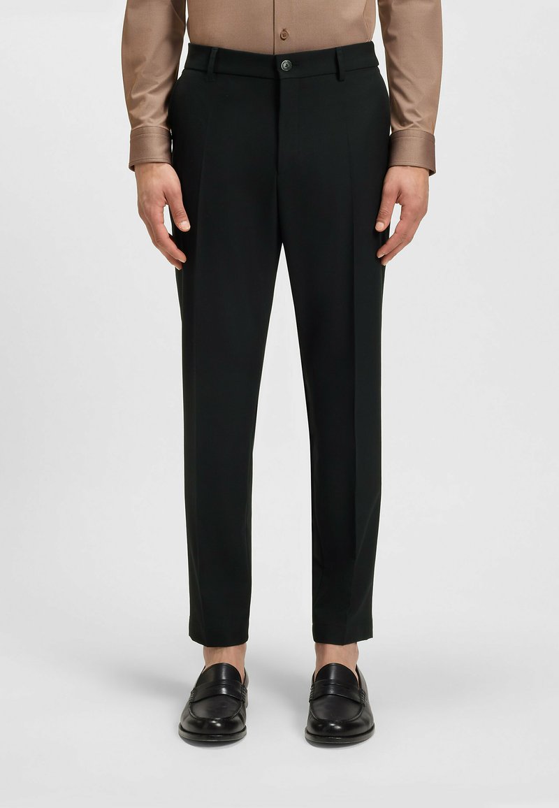 Zwarte op maat gemaakte broek met een gladde textuur, met een rechte pijp, voorkeursplooien en een knoopsluiting bij de taille.