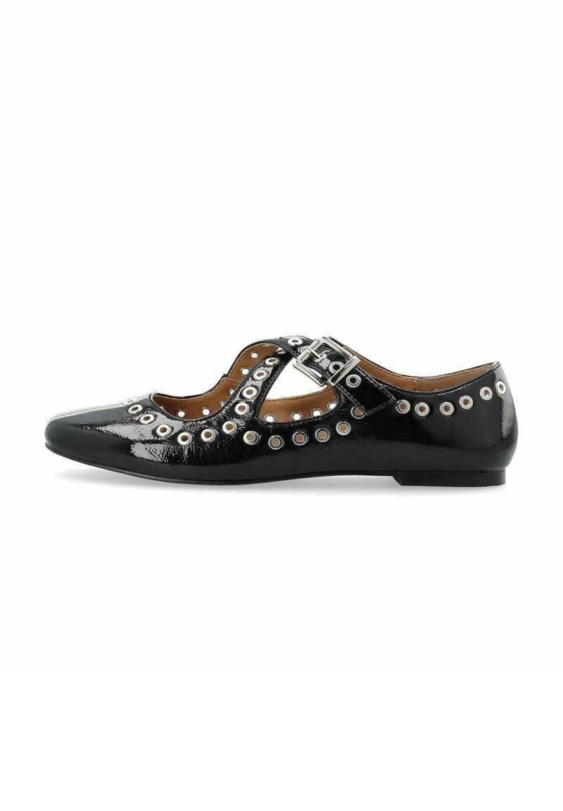 Zapato de charol negro con diseño recortado, acentos de tachuelas plateadas y correa ajustable con hebilla. Suela baja y plana. Detalles únicos a lo largo de los bordes.