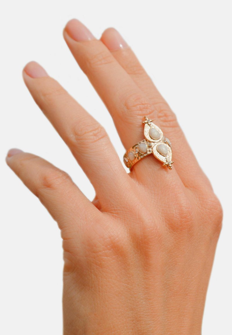 Gold ring featuring oval moonstones set in a decorative band with ornate accents. Smooth texture and intricate detailing enhance its design.