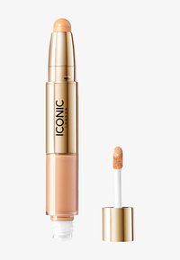Dobbeltsidig concealer med en gylden tube og rund applikatortupp, med en kremet, lys beige formel og en liten pensel-applikator.