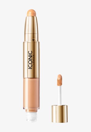 Kaksipäine peitevoide, kultaisessa putkessa ja pyöreällä applikaattorikärjellä, jossa on kermaisen kevyt beige koostumus ja pieni sivellinapplikaattori.