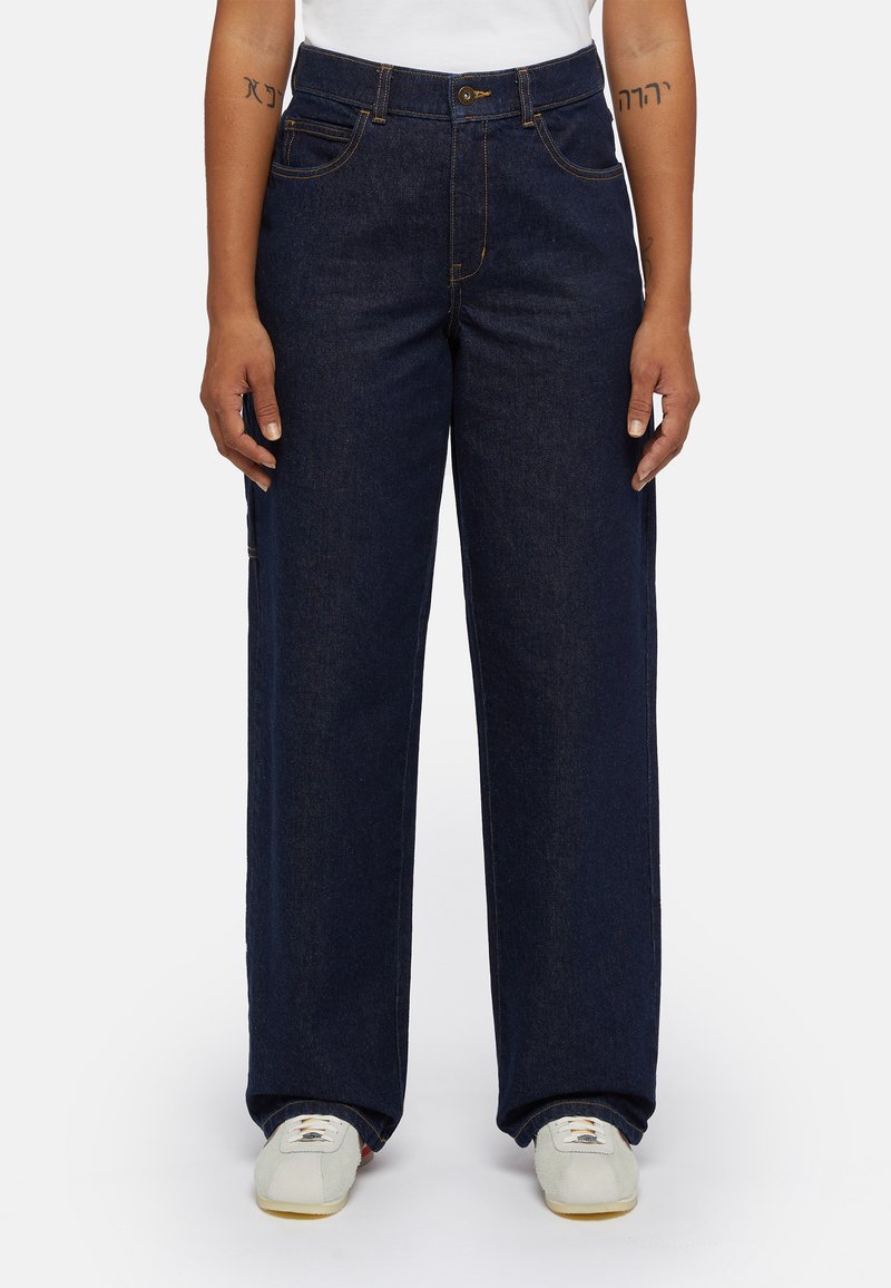 Dark blue denim wide-leg jeans with front pockets and contrasting stitching, paired with neutral-colored sneakers.