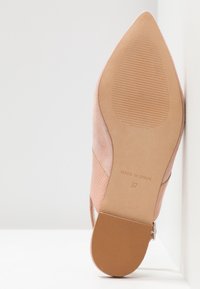 Semelle d'une chaussure pointue en daim rose avec talon texturé, marque "Made in Spain" et taille 37 visible sur fond blanc.