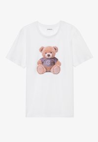 Hvit bomulls T-skjorte med en grafikk av en sittende teddybjørn som har på seg en lilla skjorte med en månegrafikk, som viser myk pelsstruktur.