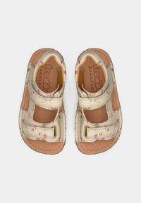 Δερμάτινα σανδάλια σε ταμπά και κρεμ αποχρώσεις με ανθώδη σχέδια, ανοικτές πλευρές, ρυθμιζόμενα λουράκια και μπεζ επενδεδυμένη σόλα για άνεση.