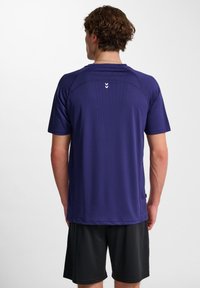 Maglietta atletica a maniche corte di colore viola scuro, realizzata in tessuto liscio e traspirante. Presenta un collo a giro e tre piccoli dettagli bianchi sul retro.