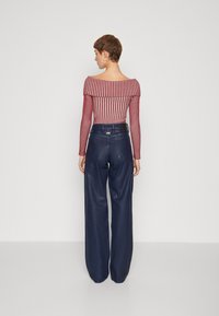Red and white striped off-shoulder top paired with high-waisted navy wide-leg trousers, featuring belt loops and back pockets.
