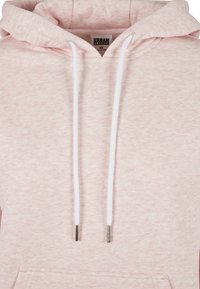 Rózsaszín kapucnis pulóver puha, texturált anyagból. Kihúzózsinórral ellátott kapucnival rendelkezik, fehér zsinórokkal és fémtiplikkel, valamint egy első kenguruzsebbel.