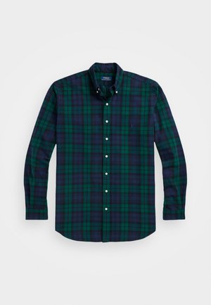 Plaid button-up shirt in dark green and navy, made of soft fabric, featuring long sleeves and a single chest pocket. White buttons throughout.