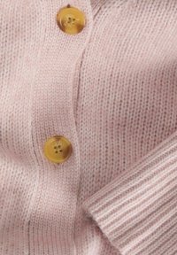 Cárdigan de punto de color rosa claro con dos grandes botones amarillos, con puños acanalados. La textura parece suave con un patrón de punto sutil y uniforme.