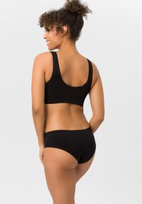 Schwarzes nahtloses Bralette- und Hipster-Unterwäsche-Set, hergestellt aus weichem Stoff mit breiten Trägern, glatten Kanten und minimalistischem Design.