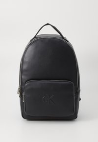 Svart läderryggsäck med rundad form, dragkedja i huvudfacket, frontficka och präglad logotyp. Har ett handtag på toppen och justerbara remmar.