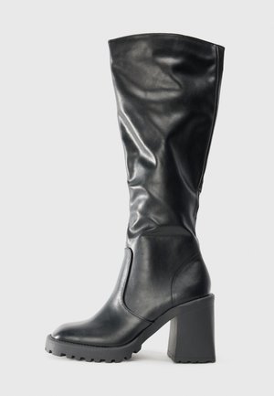 Černá kožená vysoká bota po kolena s kulatou špičkou, masivním blokovým podpatkem a texturovanou podrážkou, s měkkým, volnějším designem.