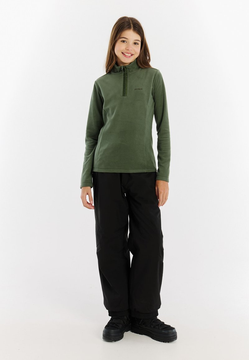 Grüner Fleece-Pullover mit hohem Kragen und Reißverschluss am Hals, kombiniert mit schwarzen wasserdichten Hosen und schwarzen Stiefeln. Einfaches, funktionales Design.