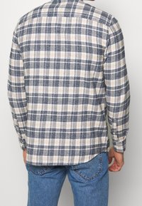 Blaues, cremefarbenes und graues kariertes Flanellhemd mit langen Ärmeln, geknöpften Manschetten und abgerundetem Saum, mit Rückenpasse und schlichtem Kragen.