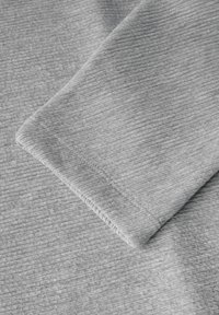 Tessuto grigio texture con un motivo a coste, morbido al tatto, con cuciture visibili lungo l'orlo.