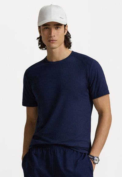 Ναυτικό μπλε αθλητικό κοντομάνικο μπλουζάκι με λαιμόκοψη και μαλακή υφή. Συνδυάζεται με σκούρες σορτς και λευκό καπέλο με λογότυπο.