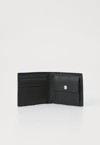 Portafoglio in pelle nera con molteplici slot per carte, chiusura a bottone a scatto e texture liscia. Presenta un logo inciso in modo discreto all'interno.