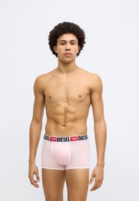 Chiloți boxer roz din material moale, cu talie elastică neagră și roșie, branduită Diesel. Design ajustat cu accente albe.