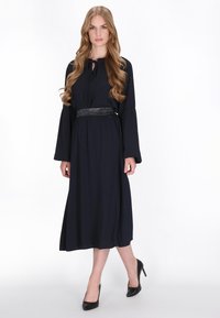 Navy maxi-jurk met wijdvallende mouwen, geplooid taillebedrijf en een metalen riem. Gladde stof en een volledige rok zorgen voor een vloeiende silhouet.