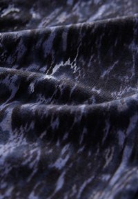 Tissu à motifs sombres avec une texture ondulée dans des nuances de bleu marine et de noir, présentant un motif marbré avec des reflets subtils.