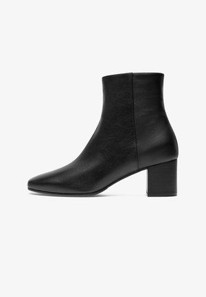 Schwarze Knöchelstiefel mit spitzem Vorderteil, aus glattem Leder gefertigt, mit einem Blockabsatz und einem nahtlosen Design für ein elegantes Aussehen.