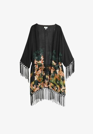 Personne portant une robe noire à fleurs nouée à la taille par-dessus un haut de bikini noir avec une boucle dorée au centre devant.