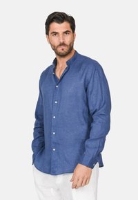 Camicia di lino blu con colletto alla coreana, maniche lunghe e chiusura con bottoni. Presenta bottoni bianchi e una vestibilità comoda senza motivi visibili.