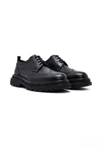 Zwarte leren brogueschoenen met een gestructureerd oppervlak, ronde neuzen en een stevige rubberen zool met diepe profielen voor grip.