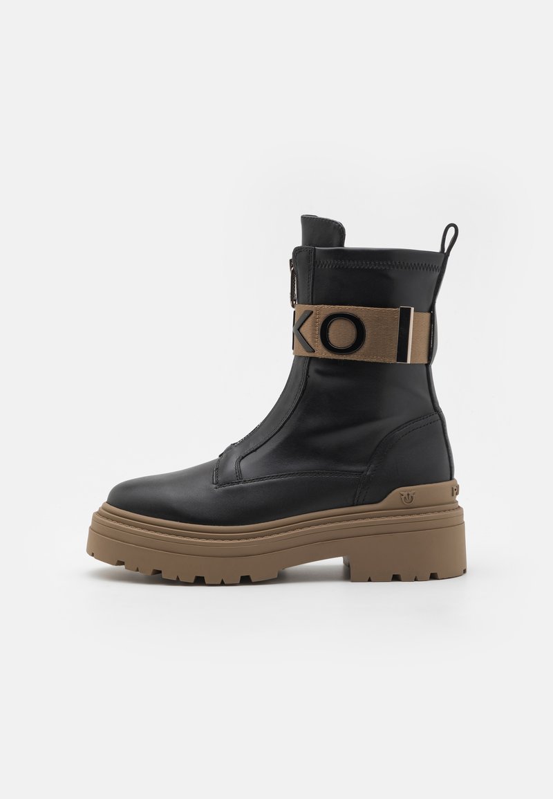 Zwarte leren enkelboot met een stevige bruine zool, voorzien van een zijrits en een merk-elastieken band met "KOI" tekstdetail.