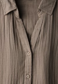 Braune, strukturierte Hemdjacke mit V-Ausschnitt und Kragen. Verfügt über vertikale Streifen und weichen Stoff. Leichtes Design mit einfachen Knöpfen.