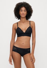 Fekete csipkés bralette és hozzáillő bugyi, amelyek ívelt szélekkel, varrat nélküli dizájnnal és finom virágmintákkal díszített derékrésszel rendelkeznek.