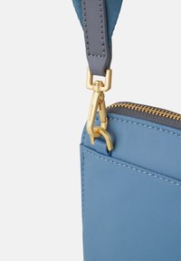 Light blue nylon bag with a gold zipper and clasp. Features a sturdy gray strap and seamless stitching on smooth surfaces.