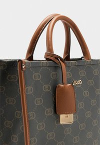 Dunkelgrüne Handtasche mit braunen Lederakzenten, mit einem Logo-Muster, strukturiertem Design, doppelten Griffen und einem goldfarbenen Hardware-Detail.
