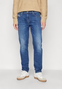 Blå denimjeans med rak passform, med en något blekt finish, fem fickor och kontrasterande sömmar. Bärs med vita sneakers.
