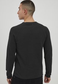 Majica z dolgimi rokavi, črna teksturirana, z okroglim izrezom in raglan rokavi, z oprijetim krojem in rebrastimi manšetami.