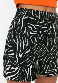 Sort/hvide zebra-stribede shorts med elastisk talje og snøre. Stoffet har et tekstureret, ribbet udseende.
