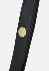 Cinghia in pelle nera con dettaglio del bottone in metallo dorato impreziosito con il nome del marchio. Presenta cuciture pulite e una superficie liscia.