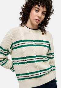 Pull en tricot crème avec des rayures vertes et bleu marine. Il présente un col côtelé, un motif de tricot en cable et une coupe décontractée.