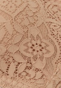 Nude koronkowa tkanina z kwiatowymi wzorami o skomplikowanych detalach, o miękkiej strukturze i delikatnym, otwartym splocie.