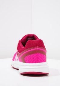Scarpa da corsa con una tomaia in mesh rosa, pannelli testurizzati e una suola bianca. Presenta un colletto imbottito e accenti a contrasto sul tallone.