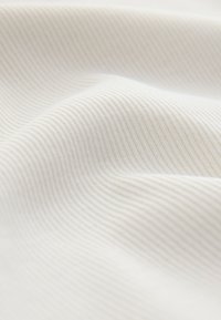 Soft white fabric with subtle vertical ribbed texture and gentle folds creating light and shadow patterns.