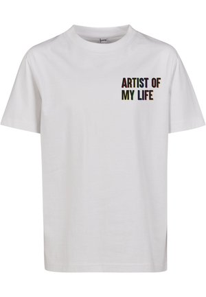 T-shirt blanche en coton à manches courtes. Texte "ARTISTE DE MA VIE" imprimé en lettres multicolores sur la zone du poitrail gauche. Encolure ronde.